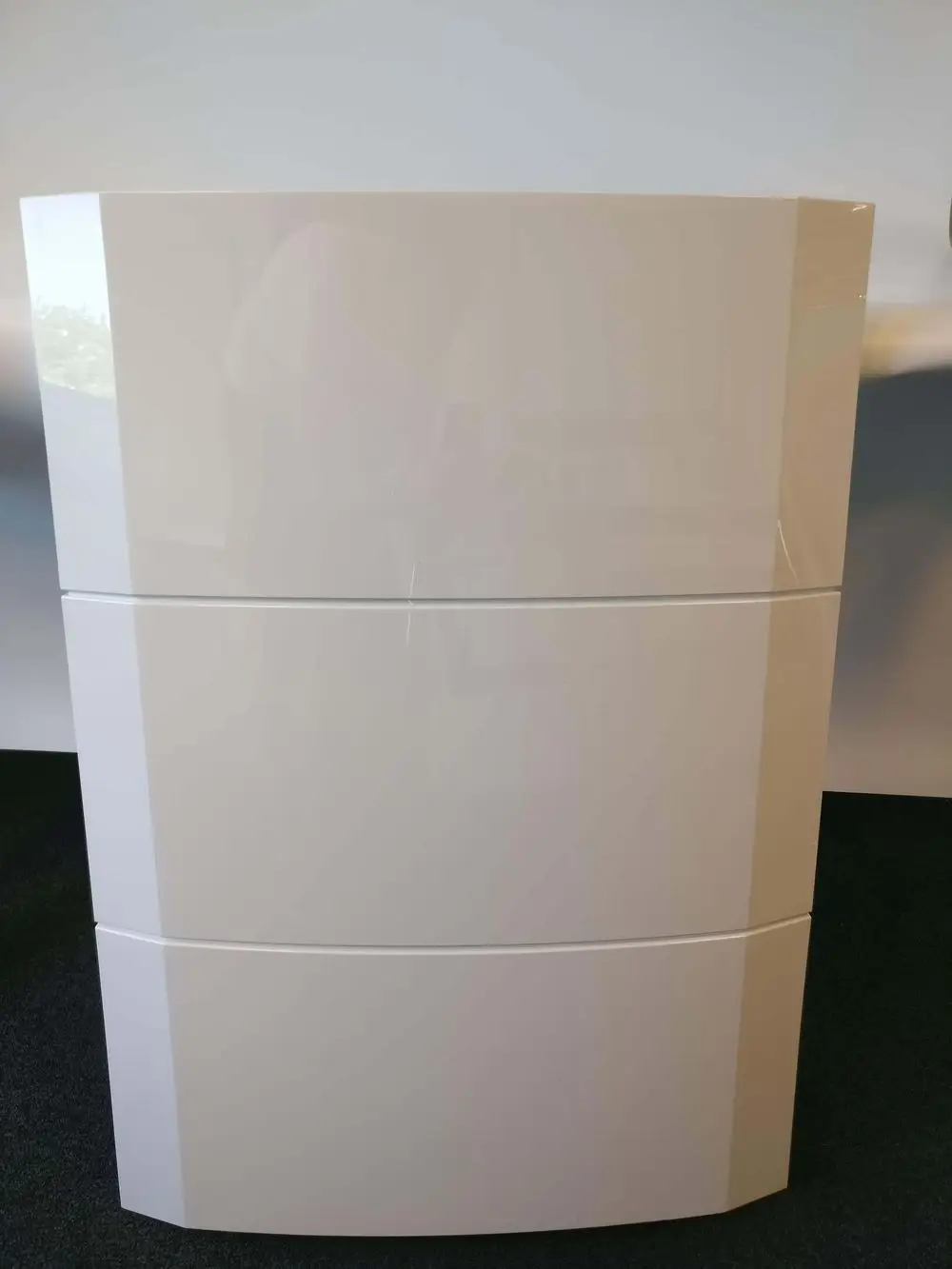 Weiße, glatte Vorderwand mit drei horizontalen Modulen, geeignet für Remeha-Produkte, in einem modernen Raum auf schwarzem Boden.